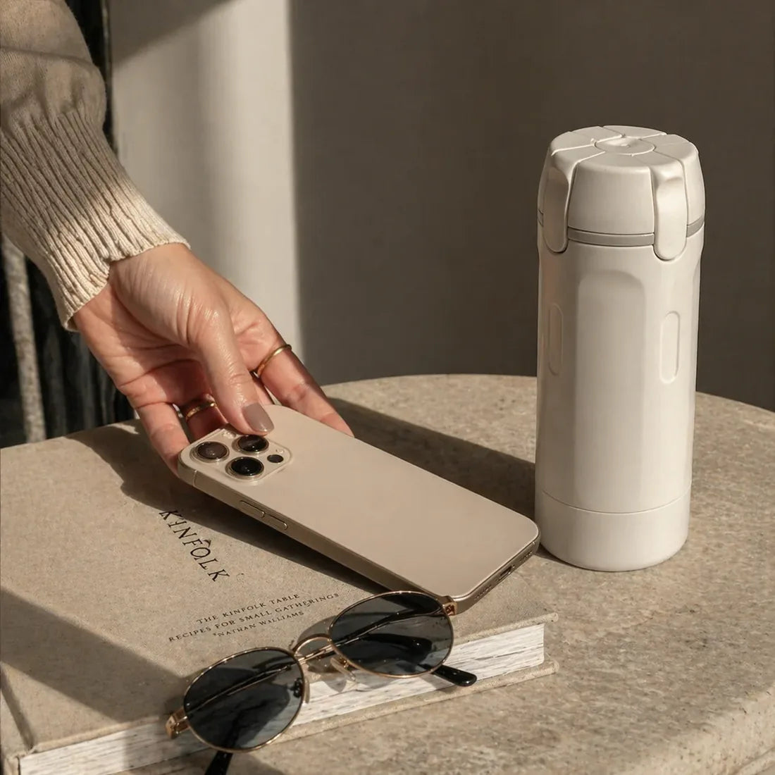 Travel dispenser on a table beside phone and sunglasses